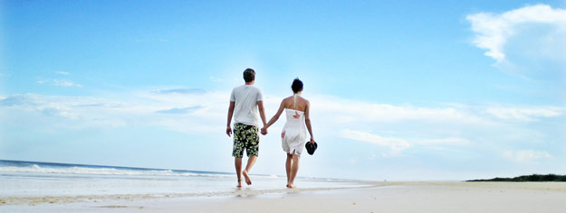 Junges Paar spaziert an einem Strand entlang